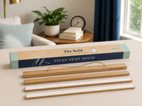 Pecan Print House wooden hanger bars and their packaging box displayed on a light beige table in a styled home interior setting.
