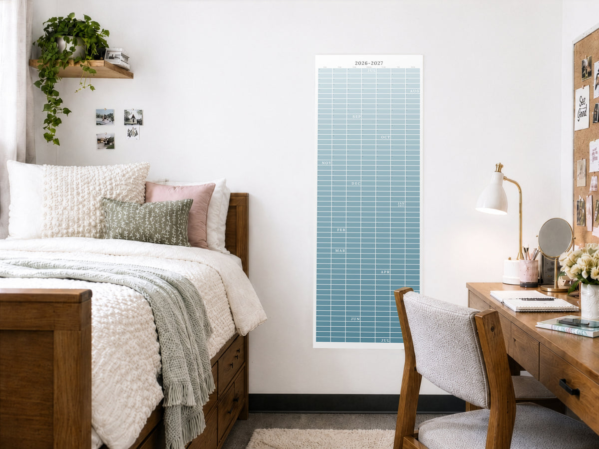 Room interior with a bed, desk, and wall calendar.